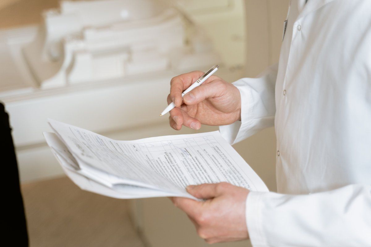 Manos del equipo médico revisando estudios y documentos impresos sobre el escritorio de un consultorio